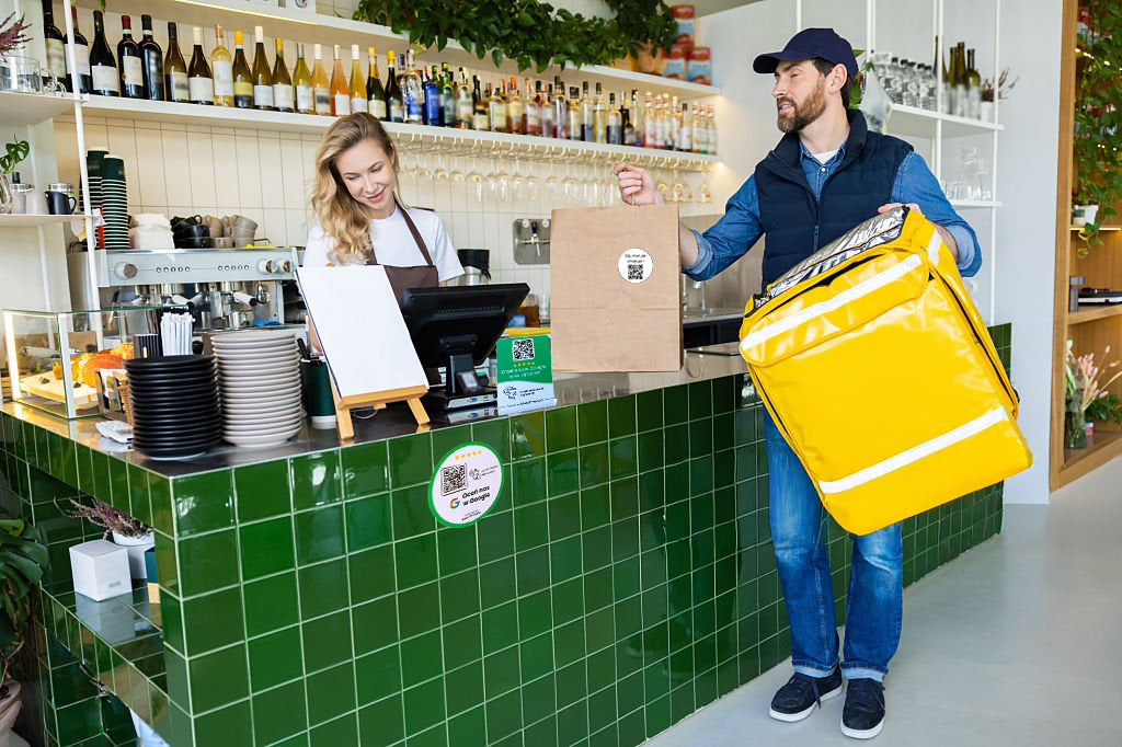 Dostawca odbierający zamówienie w restauracji – widoczne akcesoria NFC i QR