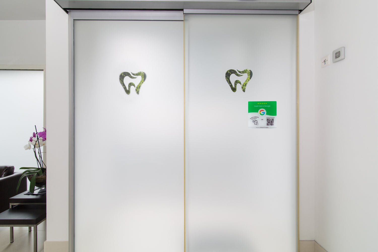 Przyciągająca wzrok zielona tabliczka z NFC i kodem QR przy wejściu; ułatwia pacjentom wystawienie opinii Google po wizycie.